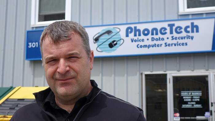 Steve Churchill dehors devant un bâtiment décoré de l'enseigne de son entreprise.