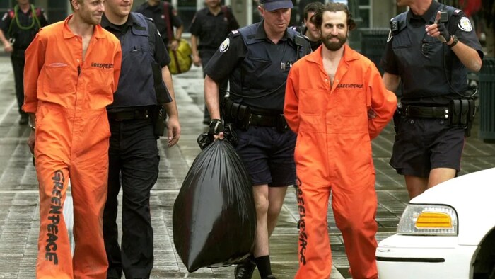 Then-Greenpeace activists Steven Guilbeault, right, 31, and Chris Holden, 23, are led by officials from the CN Tower in Toronto on July 16, 2001. Guilbeault and Holden scaled 346 metres (1,136 ft.) to protest Canada's role in changing the world's climate.