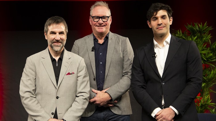 Trois hommes posent debout les mains croisés.