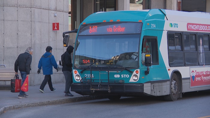 Des usagers entrent dans un autobus de la STO.