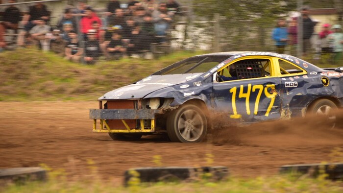 Une voiture de course de stock-car file sur une piste de terre.