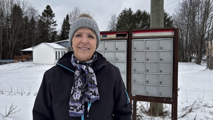 Une femme devant une boîte postale. 