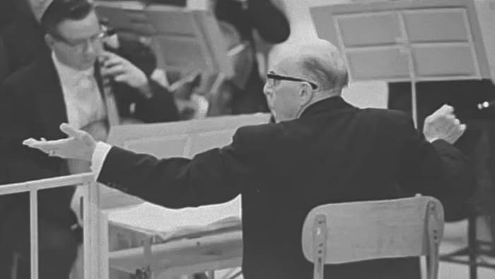 Un chef d'orchestre de dos sur scène.