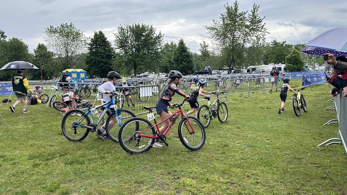 Des jeunes triathlètes agrippent leur vélo.