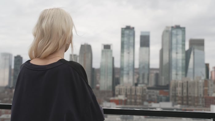 A woman looks out over the city of Montreal from behind.