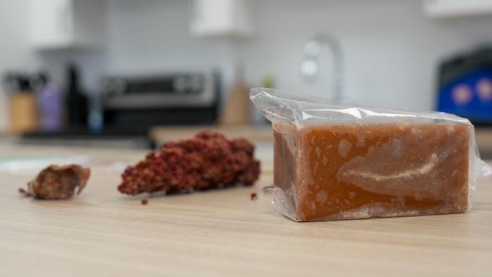 Une grappe de sumac vinagrier, un bloc de sucre du pays et du sucre du pays dans de l'écorce de bouleau.
