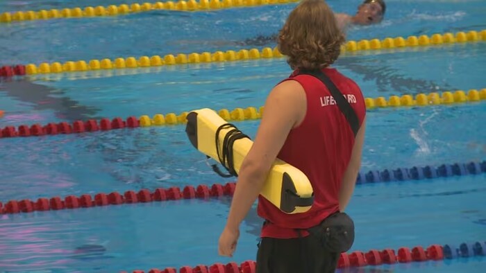 Un sauveteur observant une personne nageant dans une piscine.