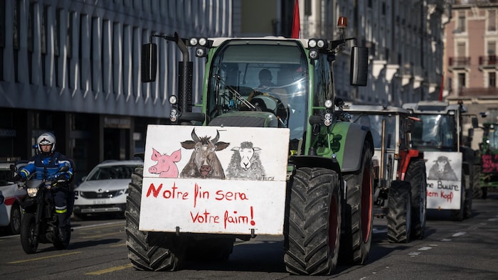 Des agriculteurs suisses, dont un avec une pancarte qui porte la mention «Notre fin sera votre faim» lors d'une manifestation contre les salaires, les impôts et la réglementation au centre-ville de Genève.