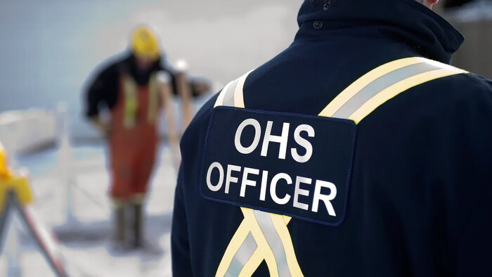Un agent de l'agence de santé et sécurité au travail de l'Alberta vu de dos.