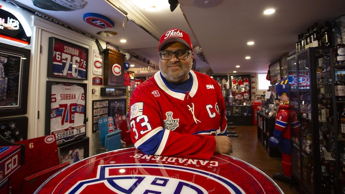Sunil Peetush prend la pose dans son sous-sol décoré aux couleurs bleu-blanc-rouge.
