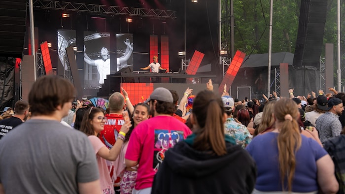 Des festivaliers au festival Sunsation écoutent un DJ.