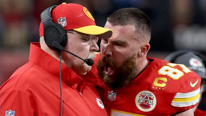 Un joueur de football américain crie au visage d'un entraîneur lors d'une partie. 