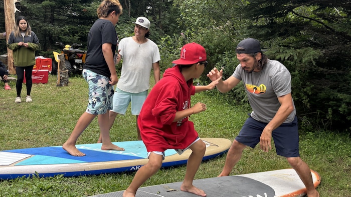 Les jeunes s'entraine sur une planche au sol.
