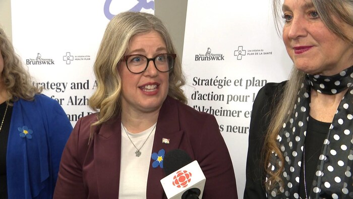 Susan Holt parle, un micro de Radio-Canada tendu vers elle, pendant que sa ministre se tient à ses côtés.
