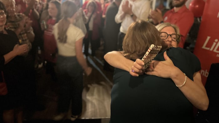 Susan Holt prends dans ses bras Hannah Fulton Johnston, devant son équipe de militants et de ministres.