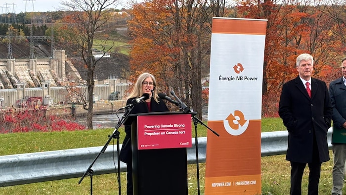 Susan Holt donne une conférence de presse devant un barrage hydroélectrique.