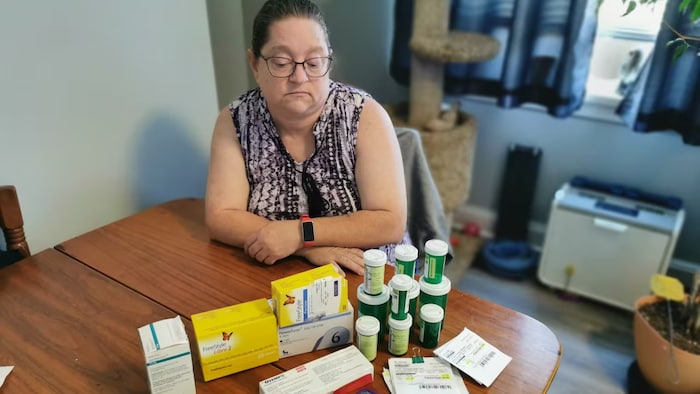 Susan Judges est assise à une table sur laquelle se trouvent des médicaments.