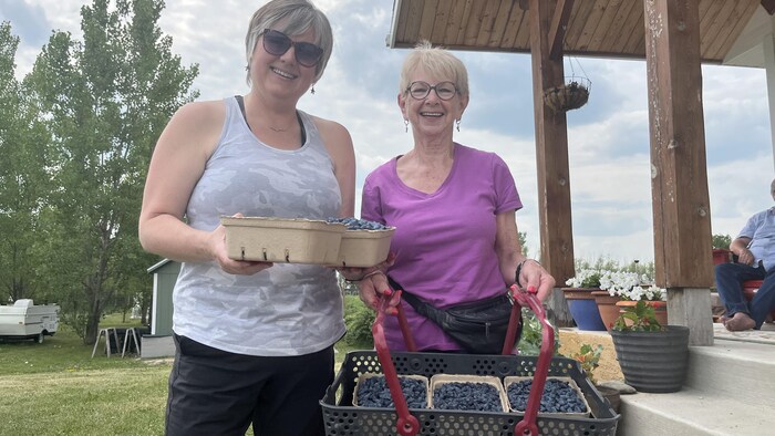 Susan Jurkowski et Barbara Reid tiennent les baies qu’elles ont cueillies dimanche, le 6 juillet 2025.