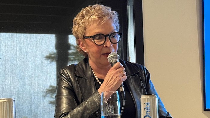Suzanne Blais parle au micro, assise en face d'une table.