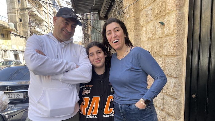 Un couple posant avec leur fille en souriant.