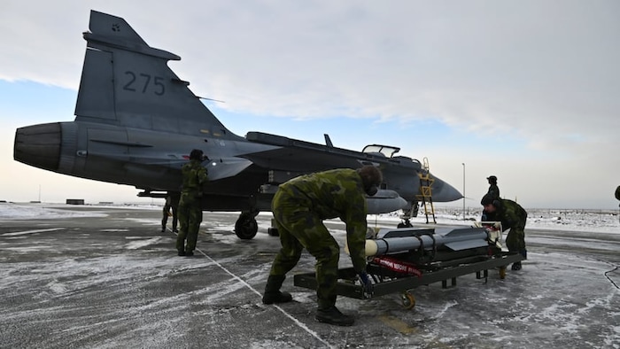 Des techniciens arment un chasseur suédois J A S 39 Gripen lors d'un entraînement de l'OTAN.