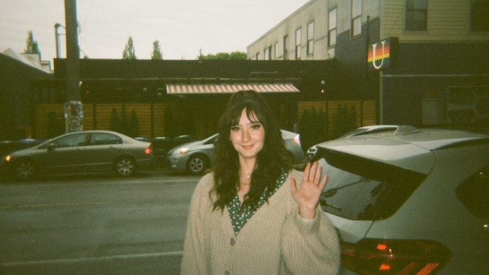 Photo de Sydney Gesualdi debout à l'extérieur, souriant et saluant la caméra avant son accident.