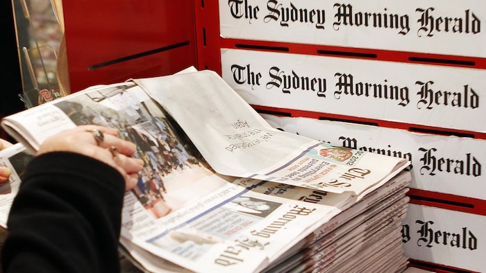 Une femme prend un exemplaire du journal Sydney Morning Herald.