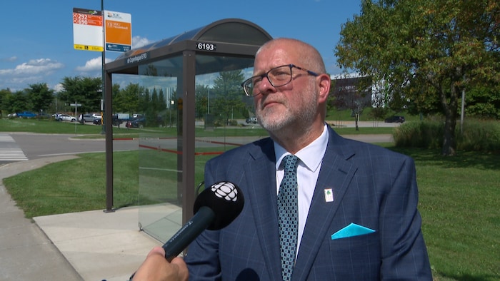 Un homme accorde une entrevue devant un abribus.