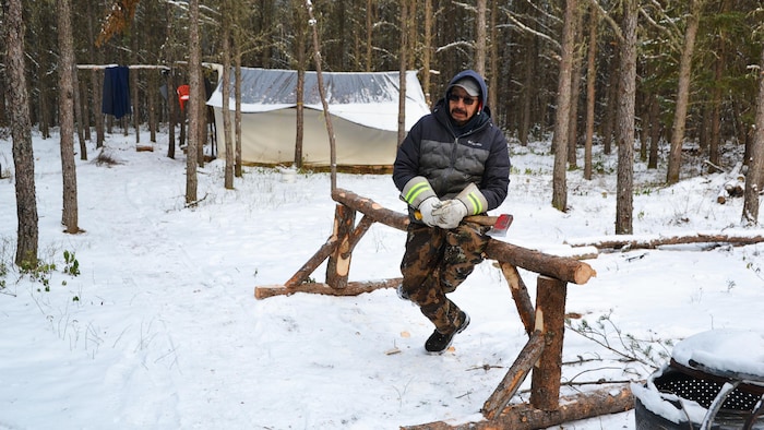 Un homme est assis sur une installation de bois.