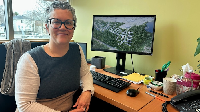 Un plan d'un nouveau développement est affiché à l'écran de Sylviane Legault qui est assise à son bureau.