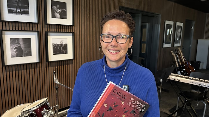 Sylvie Côté tient entre les mains l'album des finissants du Collège Saint-Bernard en 2013.