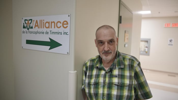 Un homme devant une pancarte de l'Allaicne de la francophonie de Timmins. 