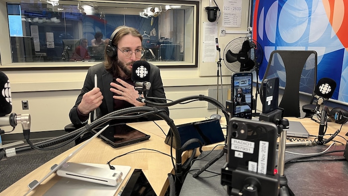 Un homme parle au micro dans un studio de radio.