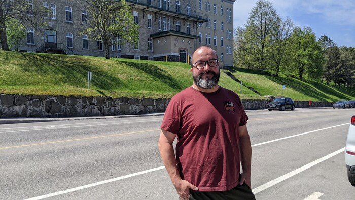 Un homme avec un chandail rouge sur le bord d'une rue.