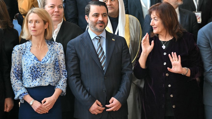 Un groupe d'hommes et de femmes debout posent pour une photo.