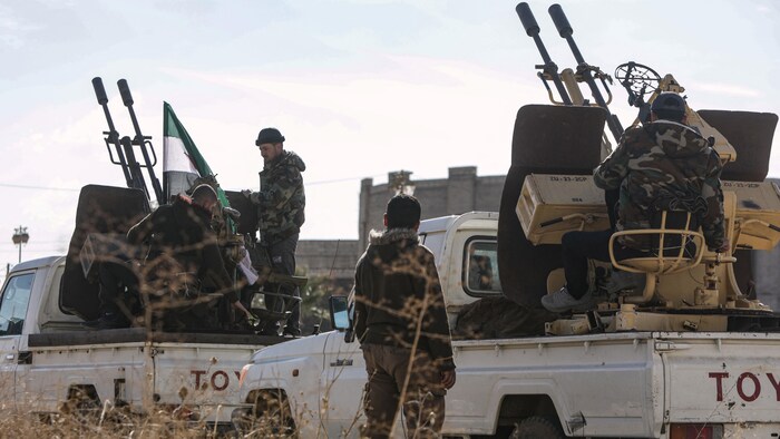Des soldats sur des camionnettes munies de mitrailleuses. 