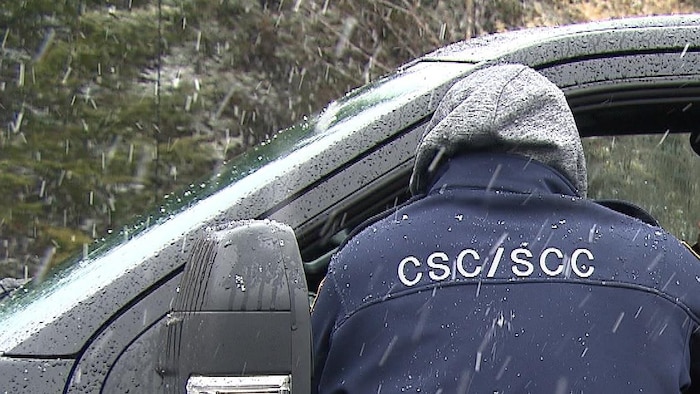 Un employé de Service correctionnel du Canada se tient sur le bord du véhicule de l'employé se rendant au travail.