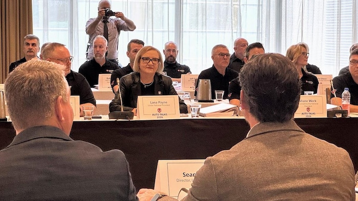 Des représentants du syndicat Unifor assis face à des représentants de Stellantis.