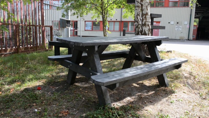 Une table à pique-nique en bois synthétique photographiée à l'extérieur, en été.