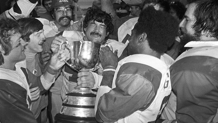 Photo en noir et blanc de footballeurs qui tiennent leur trophée.