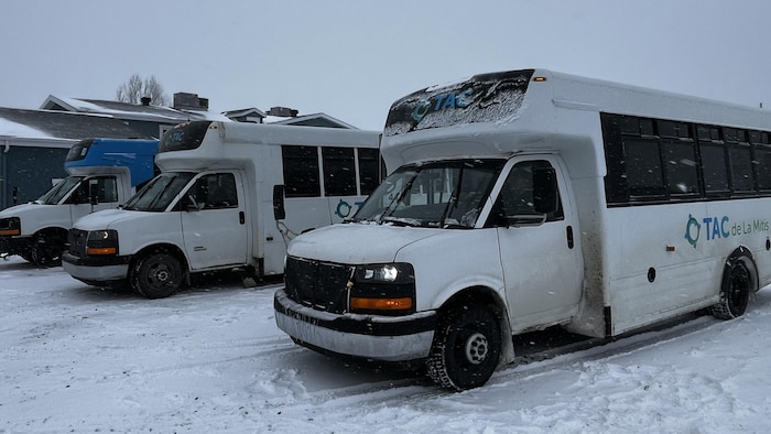Trois autobus du Transport adapté et collectif (TAC) de La Mitis dans un stationnement enneigé.