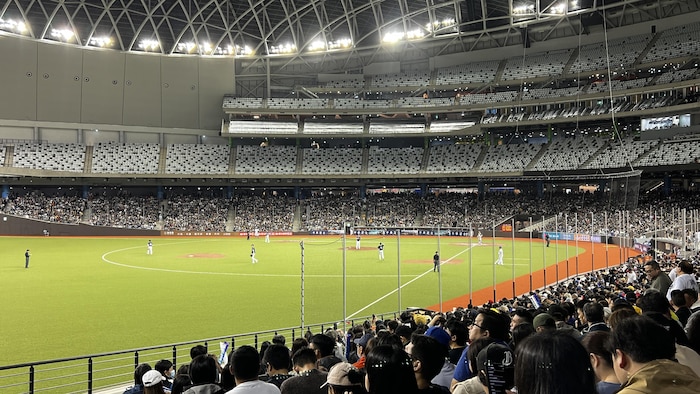 Une vue du champ gauche durant un match de baseball au Taipei Dome, où la foule occupe le premier niveau du stade.