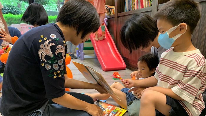 Des enfants lisent un livre avec des adultes