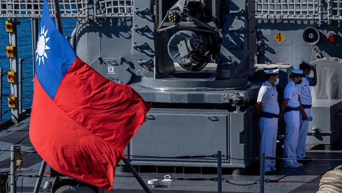 Des militaires taïwanais sur un navire de guerre, le drapeau taïwanais en avant-plan.