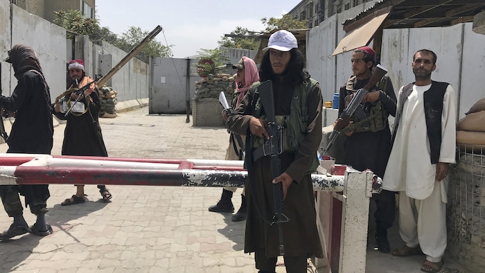 Plusieurs hommes armés dans une rue déserte.