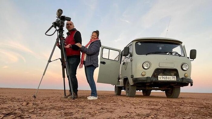 Tamara Alteresco et Alexey Sergeyev filmant dans un désert, près d'une caravane motorisée.