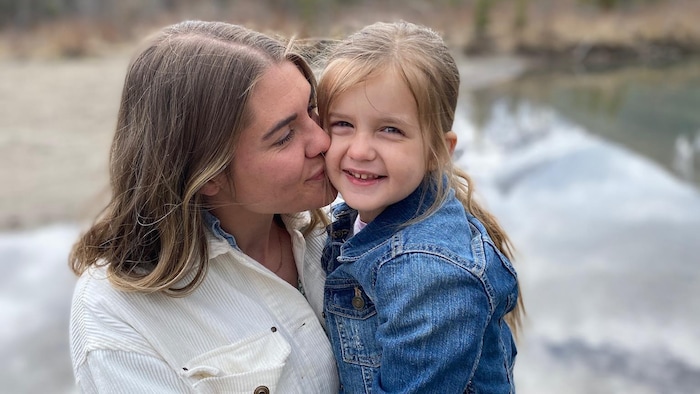 Une mère porte sa fille dans les bras.