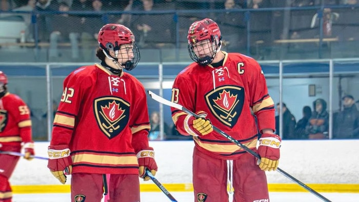 Tanner Adams parle avec un coéquipier sur la glace.