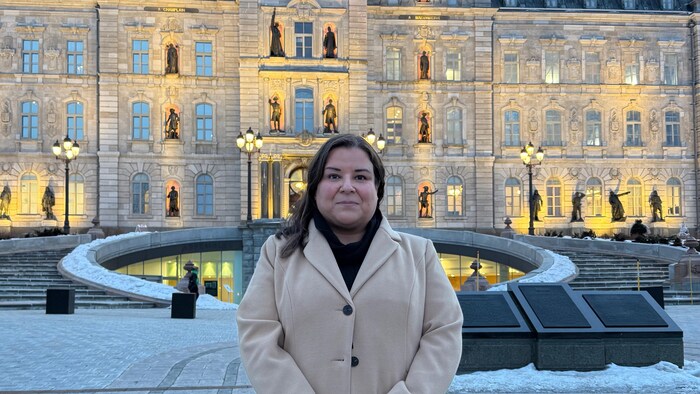 Une femme posant devant l'Assemblée nationale à Québec. 