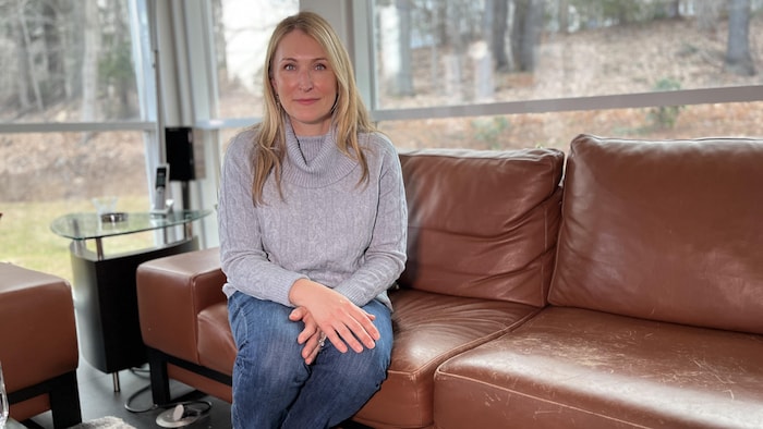 Une femme assise sur un sofa sourit.